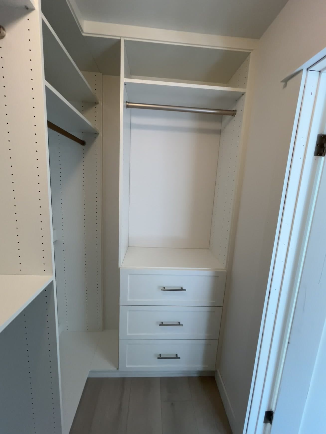 A reach-in closet fitted with double-hang sections, drawers and adjustable shelving